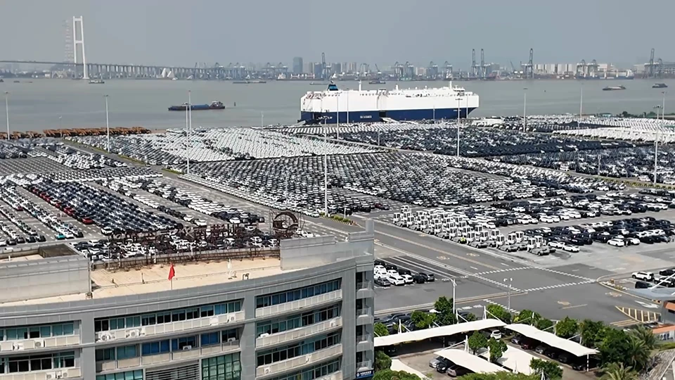 Cars at a port beside vehicle carrier ships